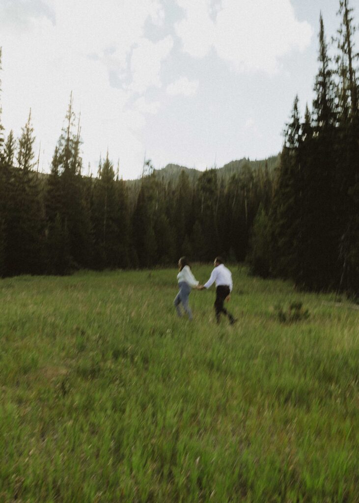 couple running in a field for their estes park engagement photos