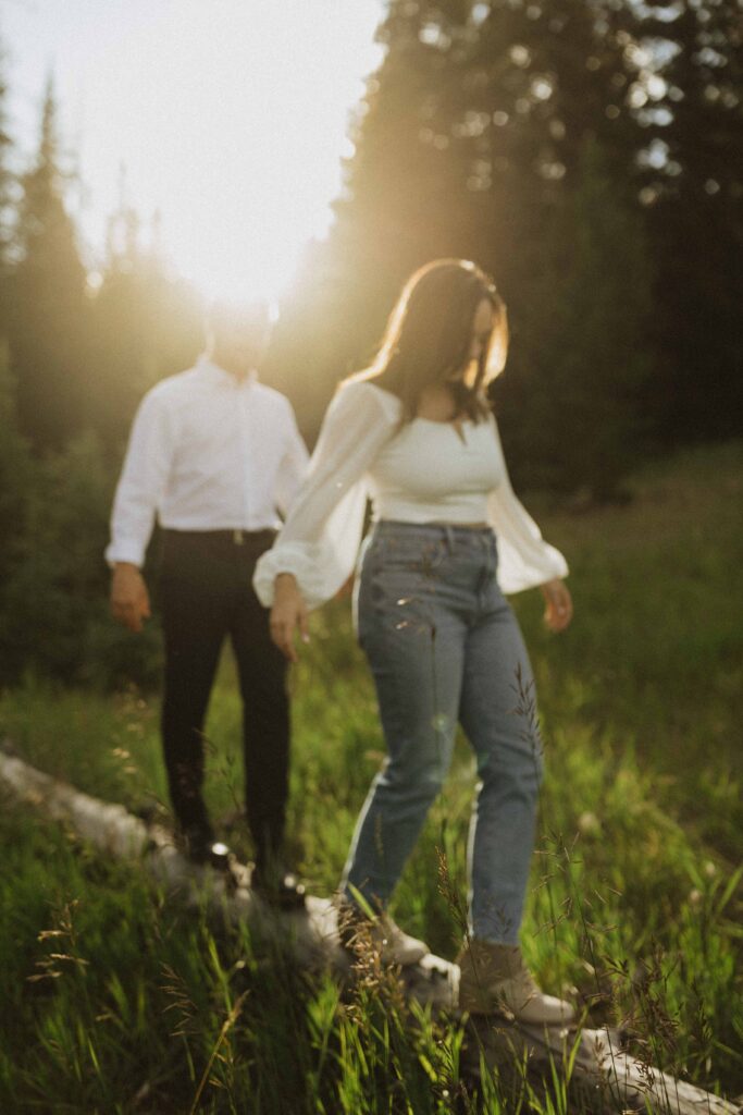a couple exploring walking a log for their engagement photos in Estes Park Colorado