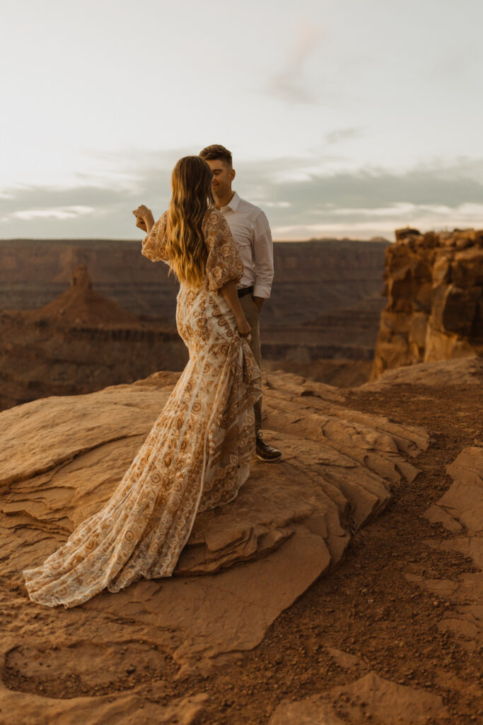 couple taking wedding photos at dead horse point in Moab at sunset