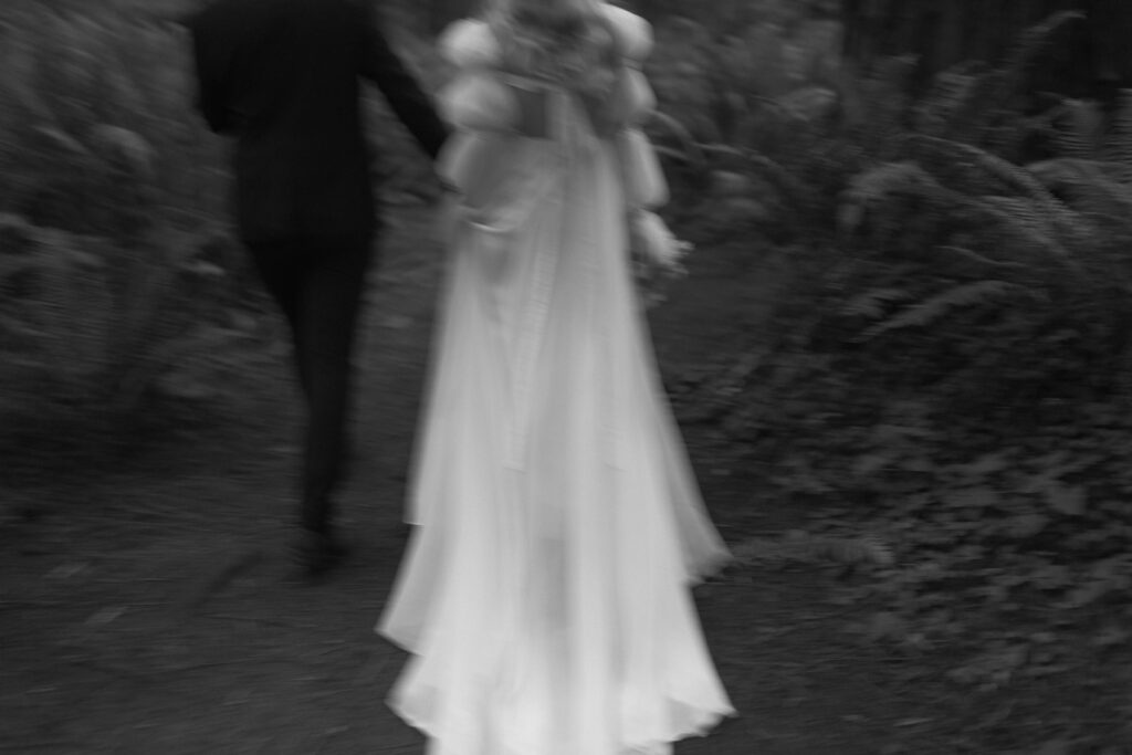 blurry photo of a bride and groom walking in the redwoods