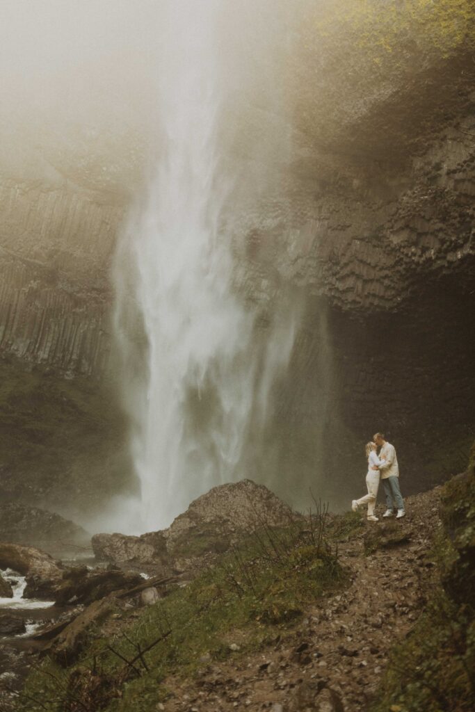 couple taking photos at their waterfall engagement photos