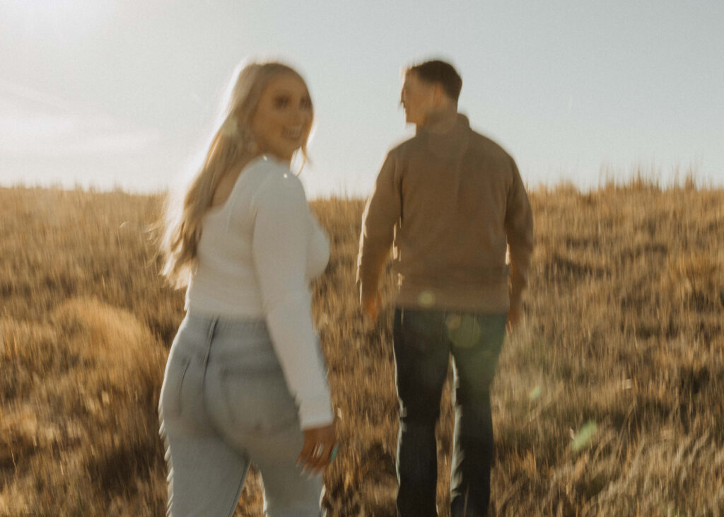 couple running around in a field for their nebraska engagement photos