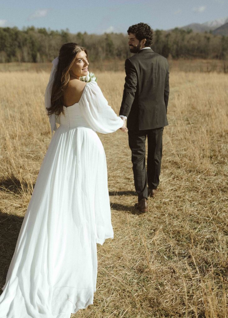 bride and groom walking while taking wedding photos at Cades Cove