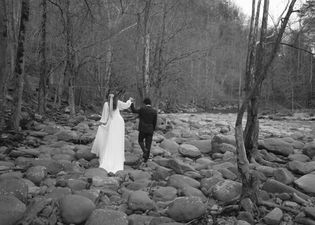 bride and groom taking photos at a river after their cades cove wedding