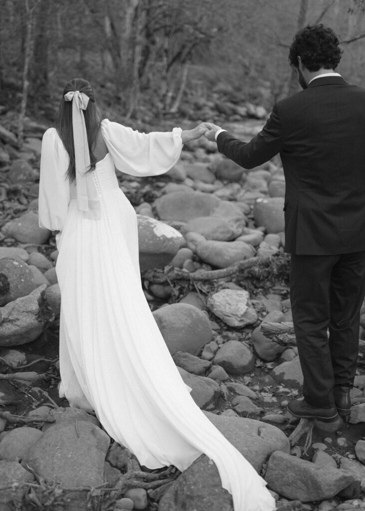 bride and groom taking photos at a river after their cades cove wedding