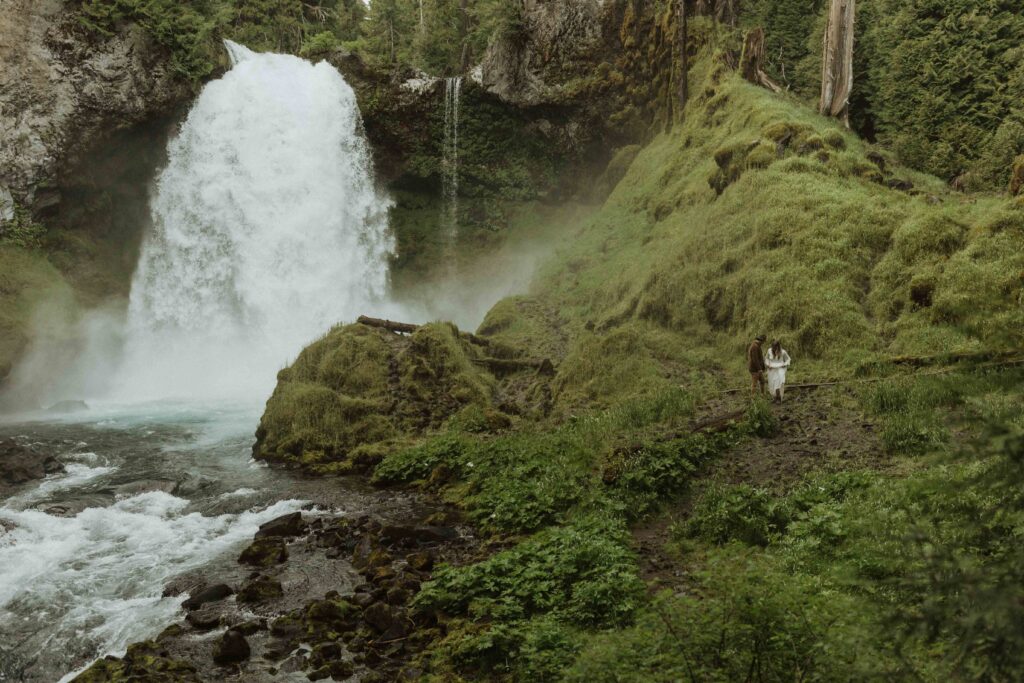 bride and groom walking at a waterfall for their elopement 