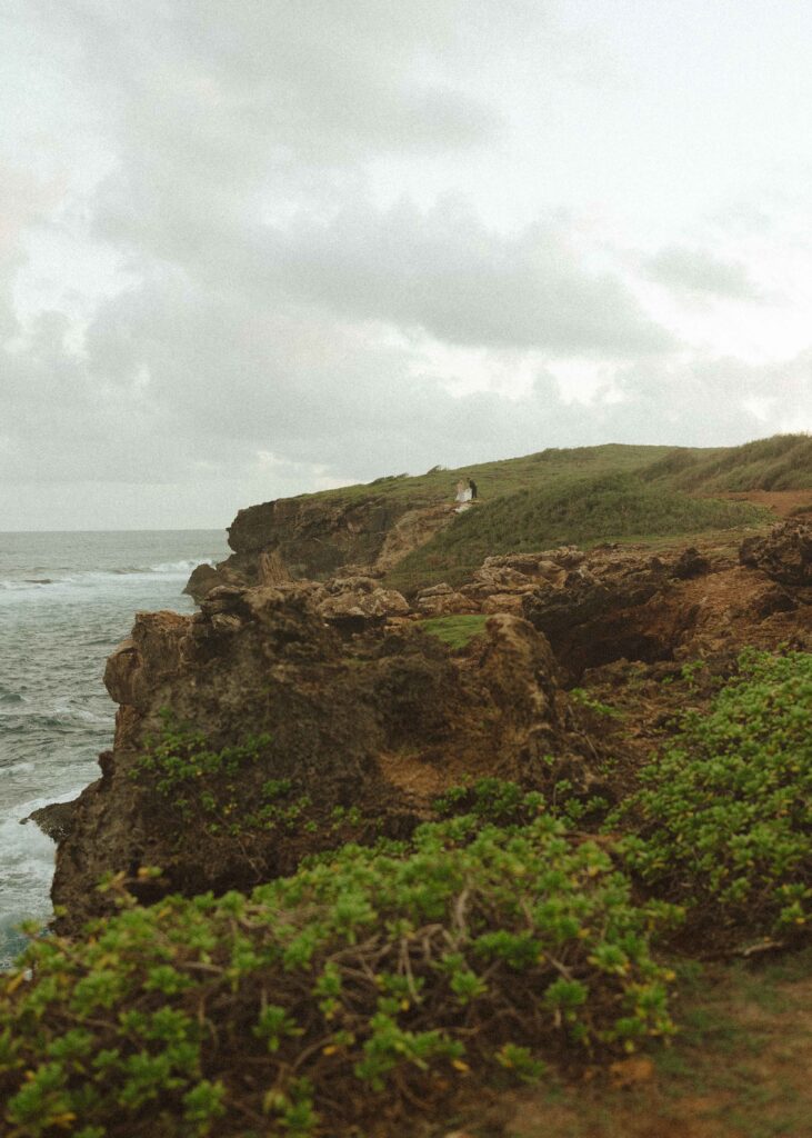 far away photo of a couple getting married on a cliffside in Hawaii