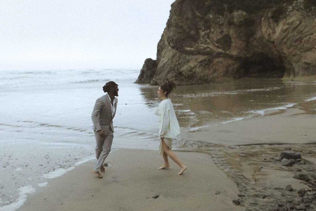 couple running on the beach for their hug point elopement 