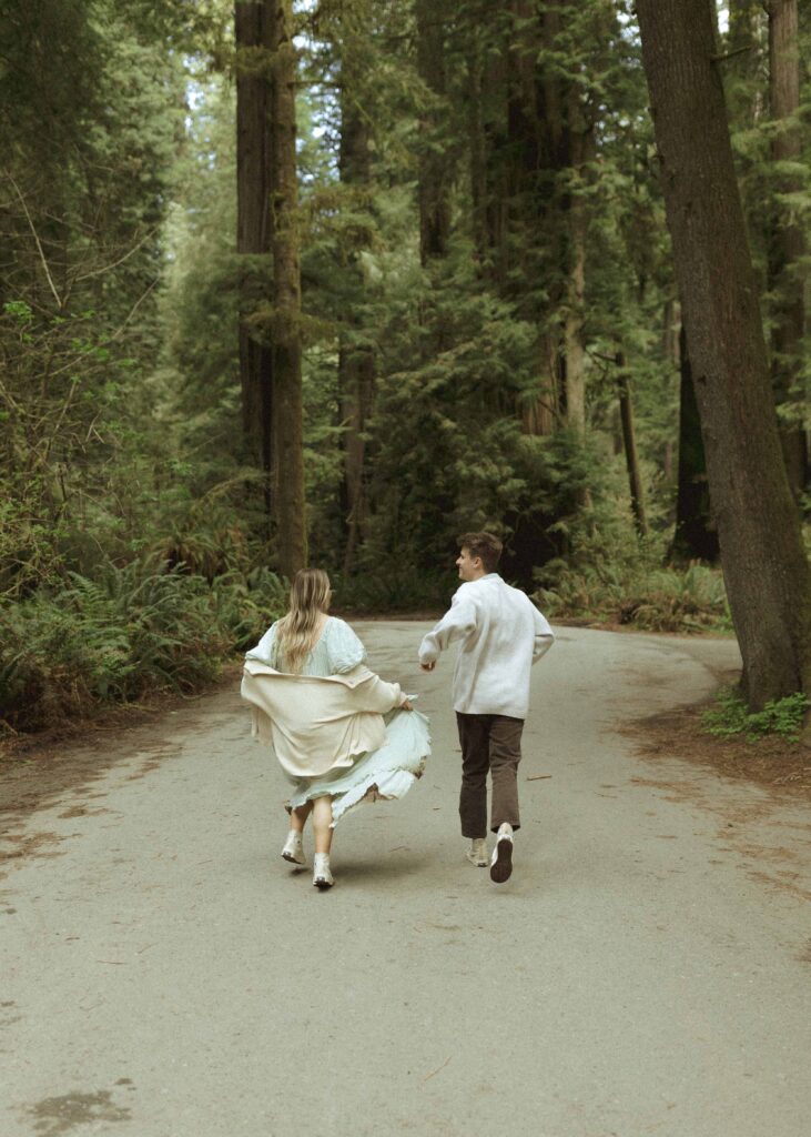 couple running on the road during their redwoods engagement photos 