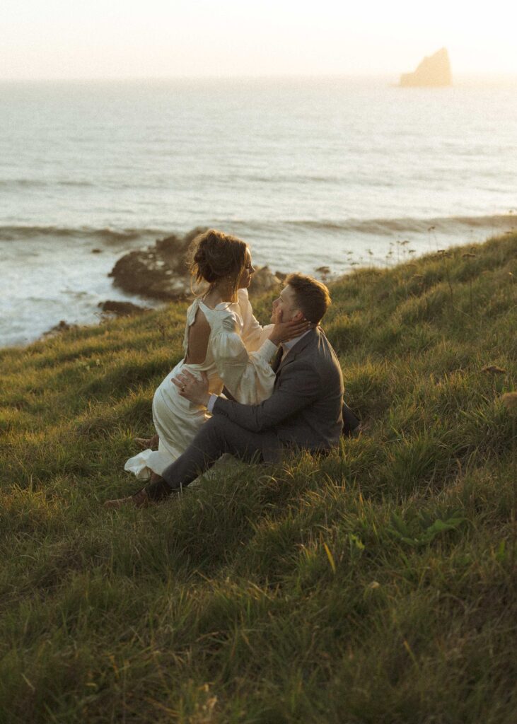 bride and groom sitting on the cliffside for their crook point elopement 
