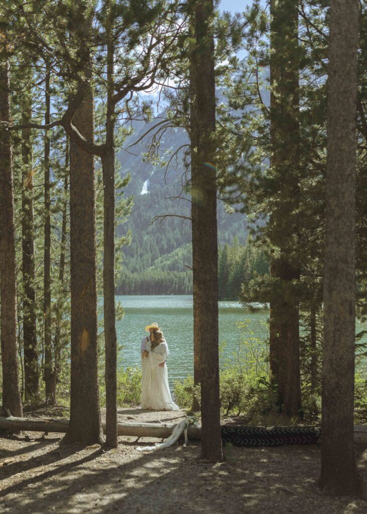 couple taking photos at a lake before their mountain view turnout wedding 