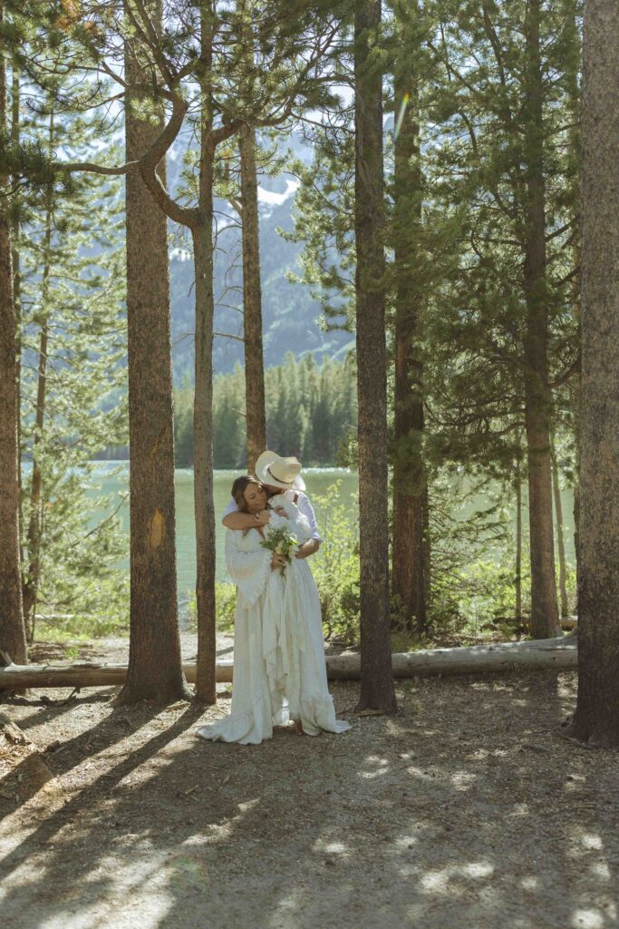 couple taking photos at a lake before their mountain view turnout wedding 