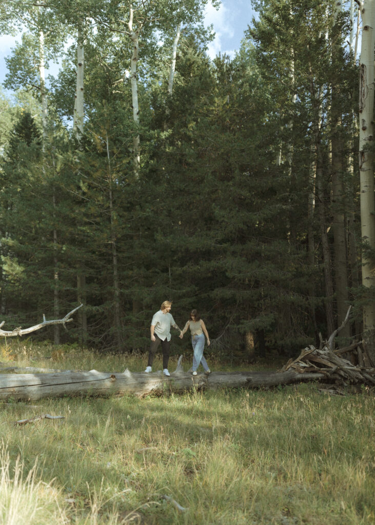 couple walking on a log for their flagstaff engagement photos