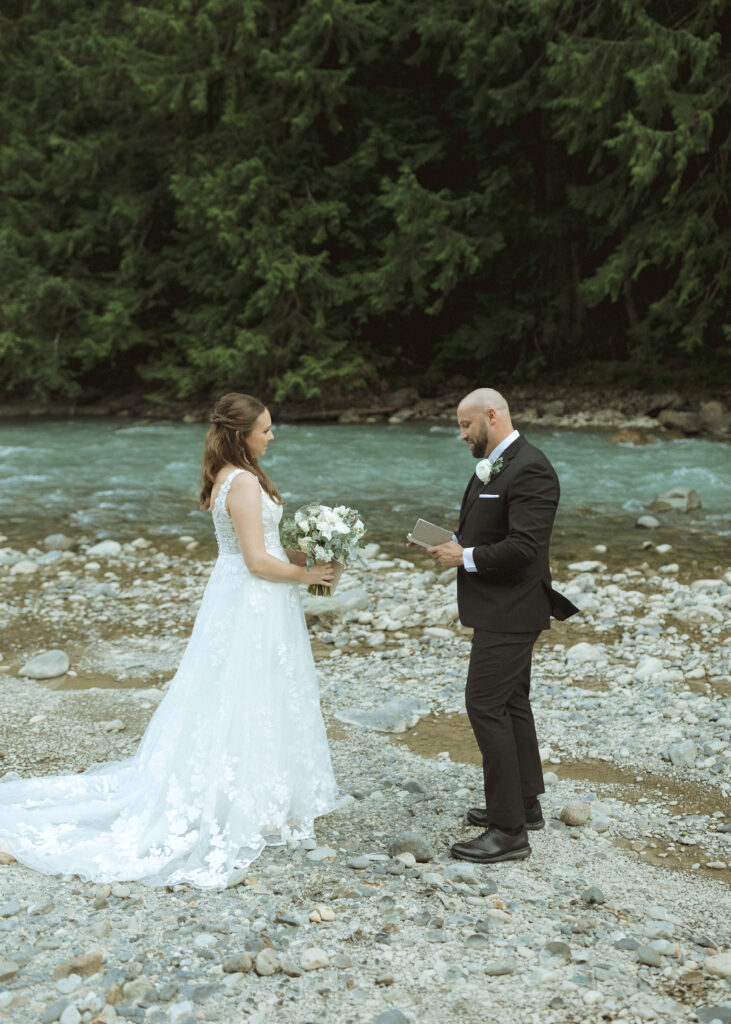 bride and groom reading their vows along the river for their Mount Baker Elopement 