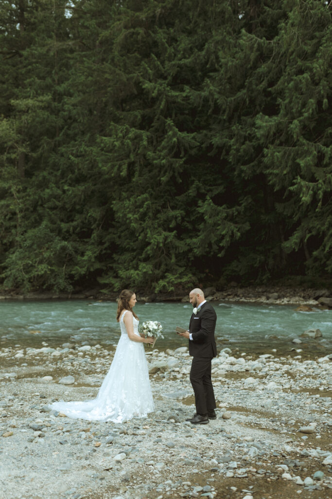 bride and groom reading their vows along the river for their Mount Baker Elopement 