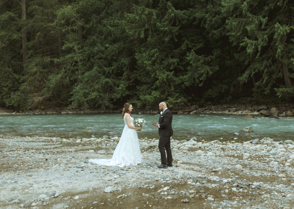 bride and groom reading their vows along the river for their Mount Baker Elopement 