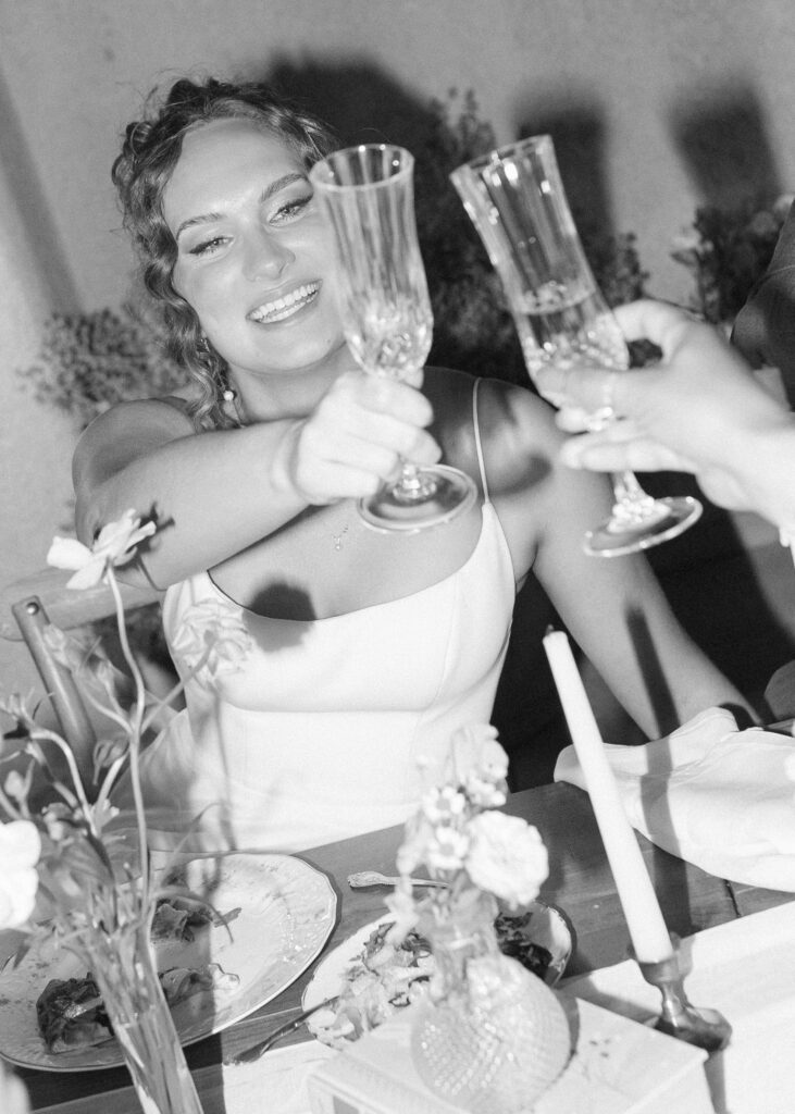 bride cheers during elopement dinner