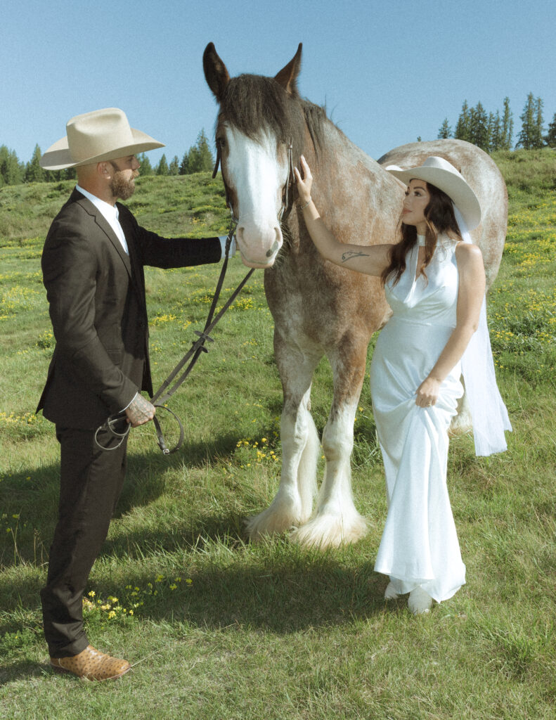 couple taking photos with horses after their lake McDonald elopement