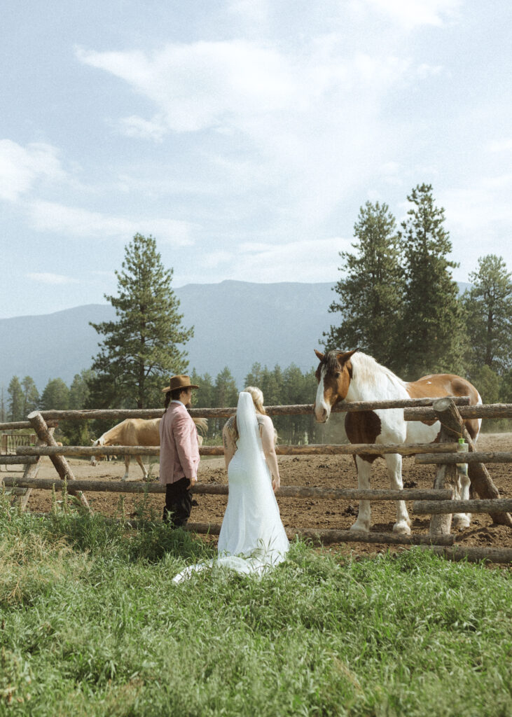 couple taking photos with the horses for their logan pass elopement