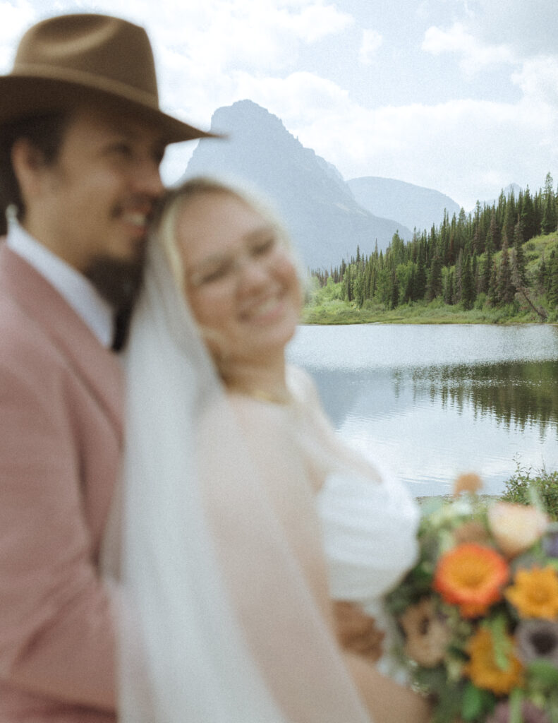 couple taking photos at a lake before their logan pass elopement
