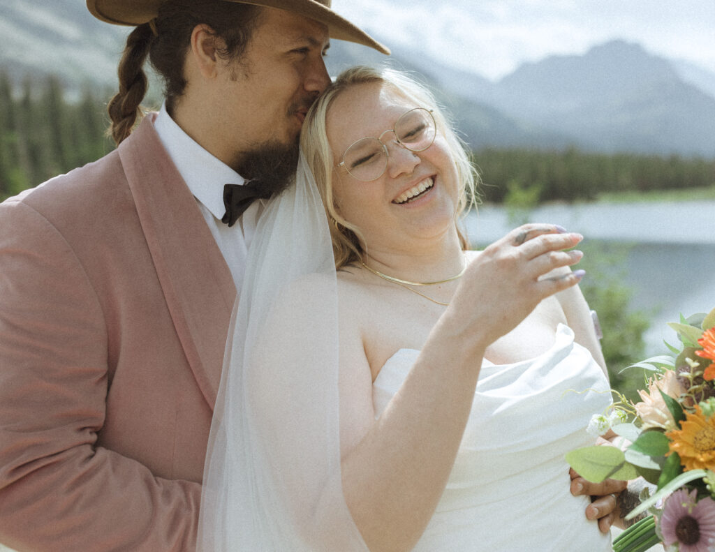 bride and groom taking photos at a lake before their logan pass elopement