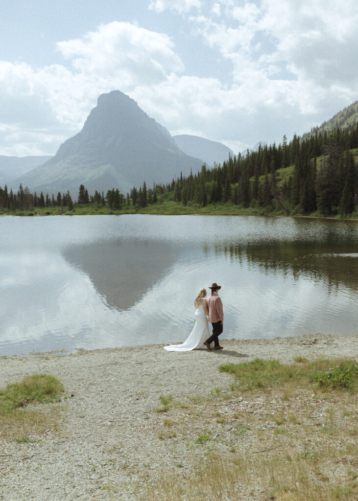 couple taking photos at a lake before their logan pass elopement