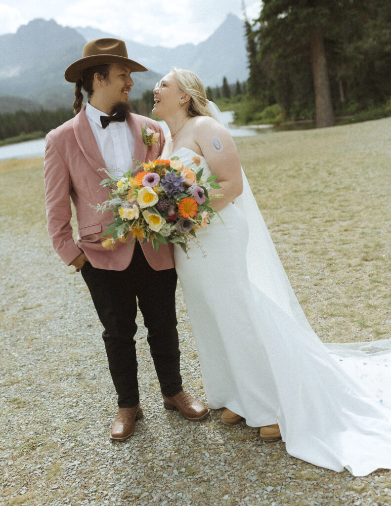 couple taking photos at a lake before their logan pass elopement
