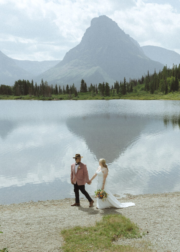 couple taking photos at a lake before their logan pass elopement