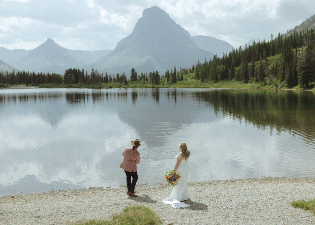 couple taking photos at a lake before their logan pass elopement