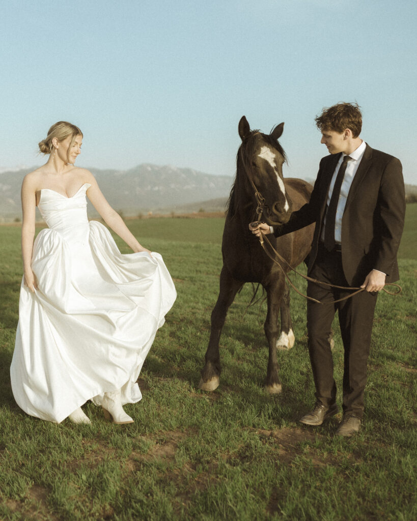 couple taking photos with horses for their Wyoming horse elopement
