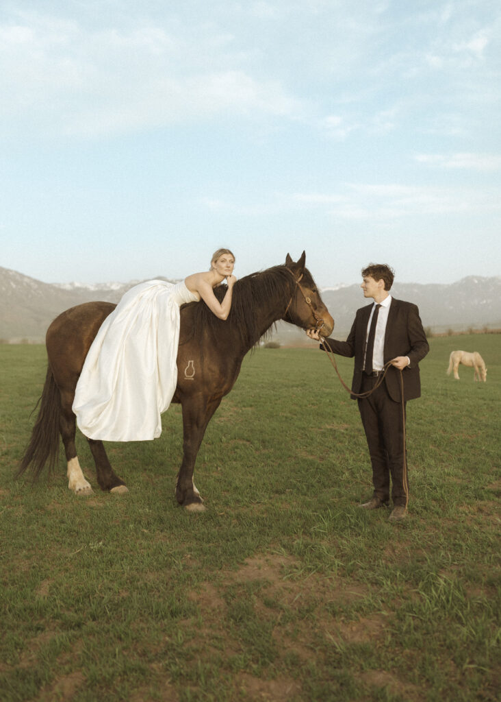 couple taking photos with horses for their Wyoming horse elopement
